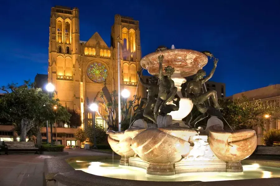 La Grace Cathedral di San Francisco è raffigurata di notte con una fontana decorata in primo piano.